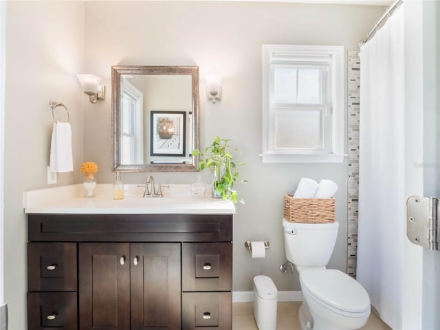 bathroom with a wealth of natural light, baseboards, vanity, and toilet