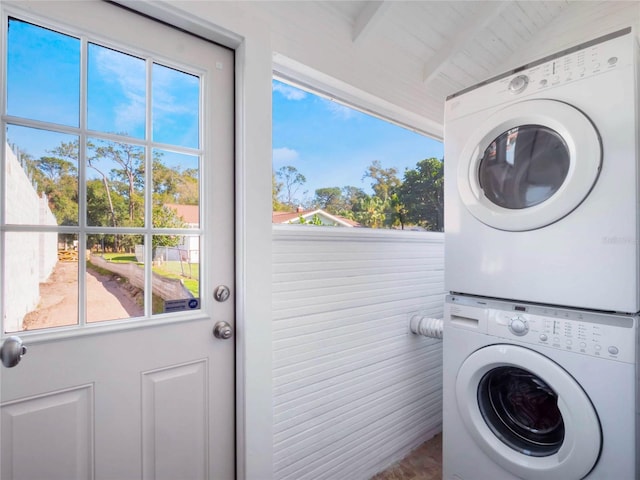 laundry area with stacked washer / dryer, laundry area, and plenty of natural light