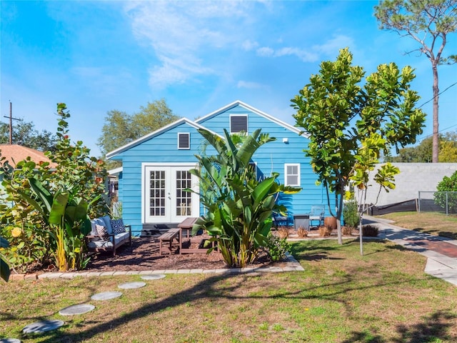 exterior space with fence, a lawn, and french doors