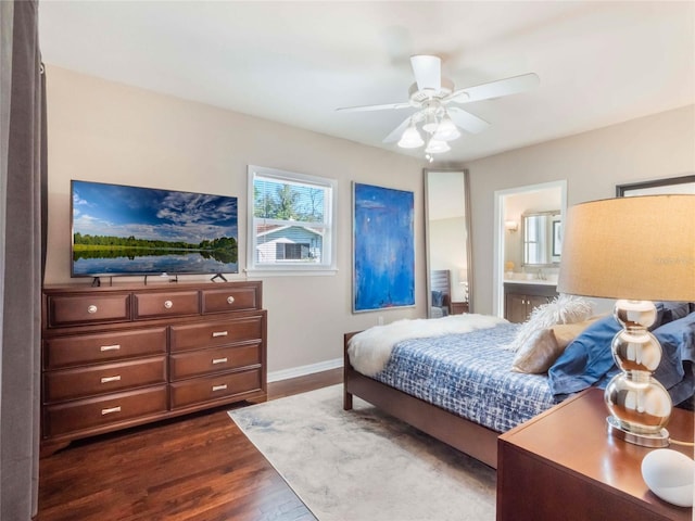 bedroom featuring dark wood-style floors, ceiling fan, baseboards, and connected bathroom