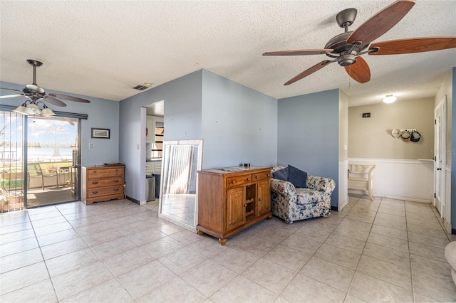 kitchen featuring a textured ceiling, light tile patterned flooring, visible vents, and brown cabinets