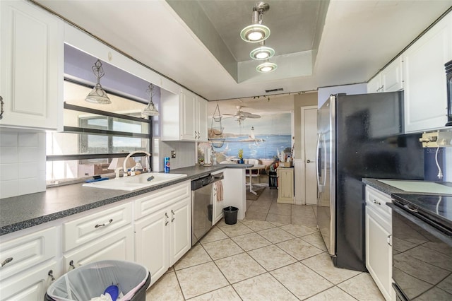 kitchen with light tile patterned floors, decorative backsplash, dishwasher, a tray ceiling, and a sink