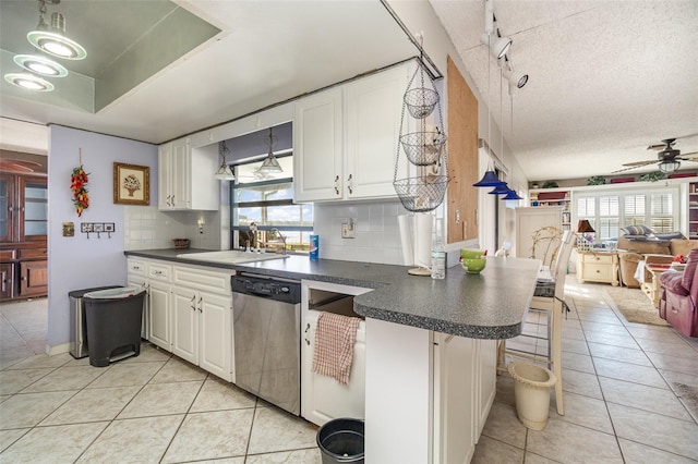 kitchen with light tile patterned floors, decorative backsplash, dishwasher, dark countertops, and a sink