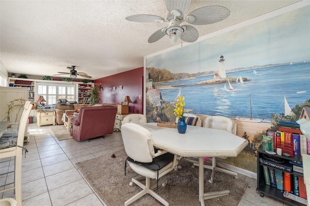 dining space with a textured ceiling, ceiling fan, light tile patterned floors, and a water view