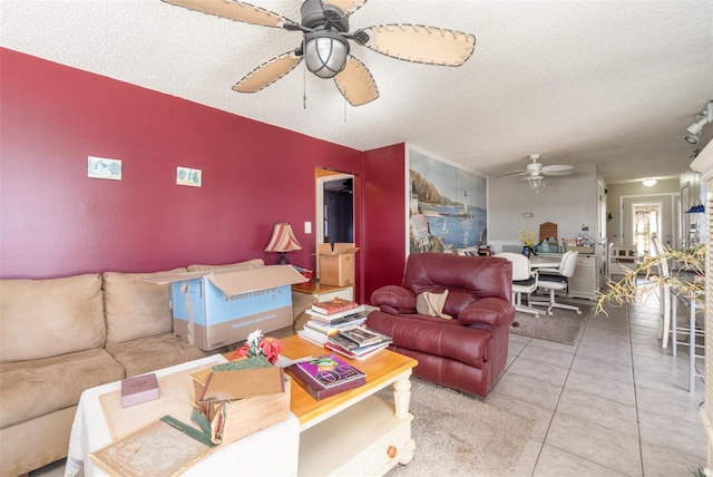 tiled living room featuring ceiling fan, an accent wall, and a textured ceiling