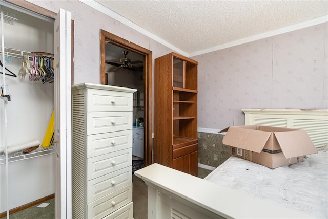 bedroom with crown molding, a closet, a textured ceiling, baseboards, and wallpapered walls