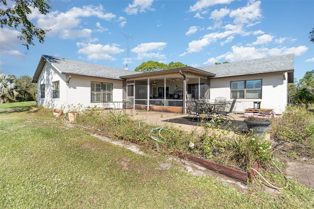 rear view of house with a yard, a patio area, a sunroom, and stucco siding