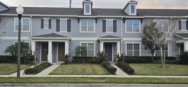 view of property featuring a front lawn and stucco siding