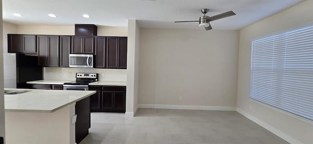 kitchen featuring stainless steel appliances, a ceiling fan, baseboards, light countertops, and decorative backsplash