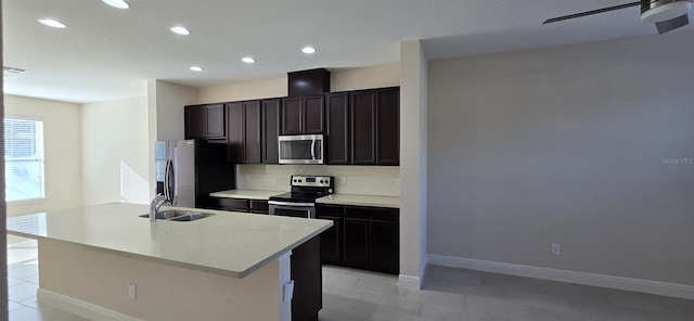 kitchen with stainless steel appliances, light countertops, backsplash, a kitchen island with sink, and a sink