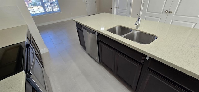 kitchen with light stone counters, a sink, baseboards, stainless steel dishwasher, and dark cabinetry