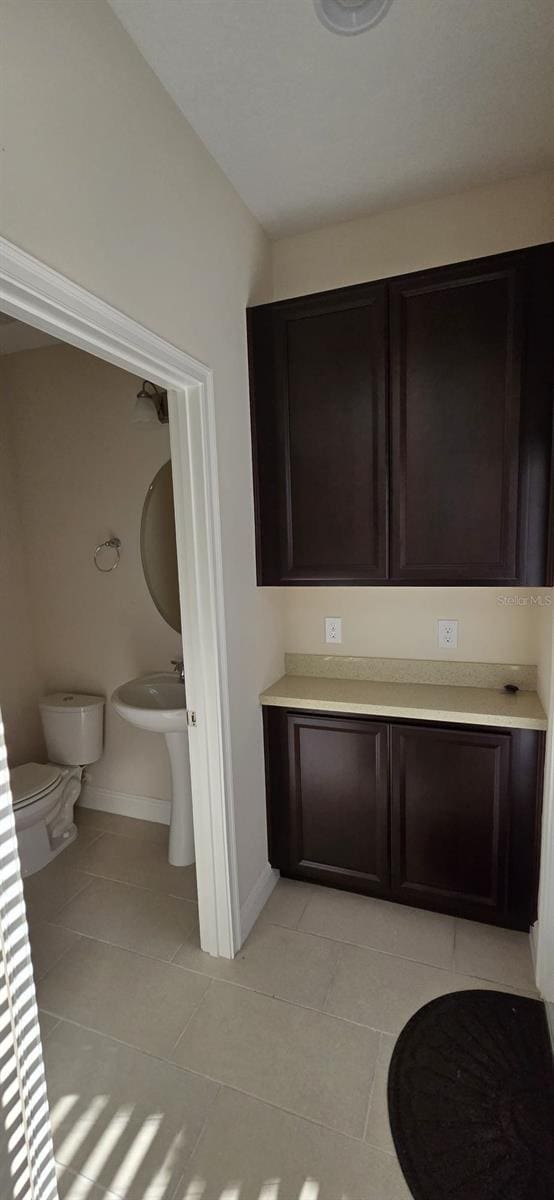 half bathroom featuring baseboards, toilet, and tile patterned floors