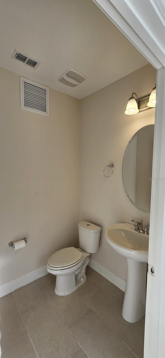 bathroom featuring toilet, baseboards, visible vents, and tile patterned floors