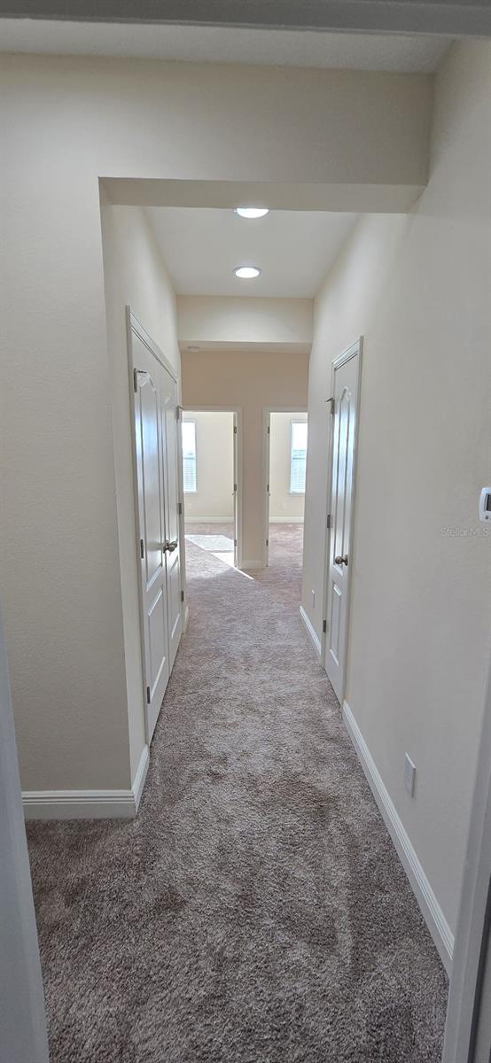 hallway featuring carpet and baseboards