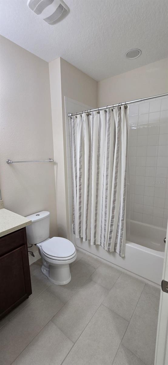 bathroom with toilet, visible vents, vanity, tile patterned floors, and shower / bathtub combination with curtain