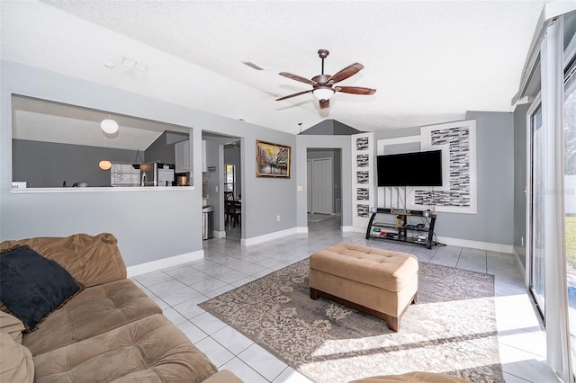 living area with baseboards, visible vents, lofted ceiling, ceiling fan, and tile patterned flooring