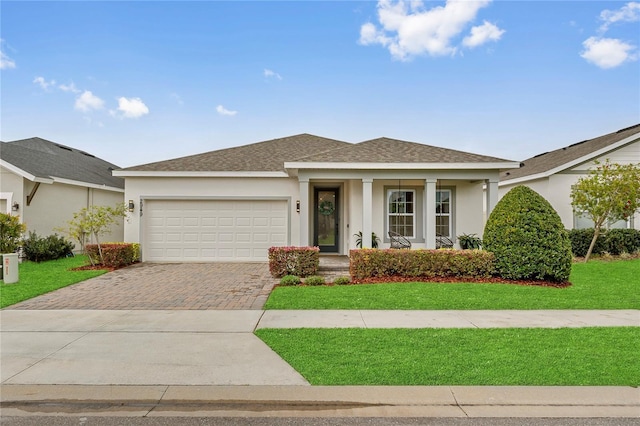 view of front of home featuring a garage, decorative driveway, a front lawn, and stucco siding