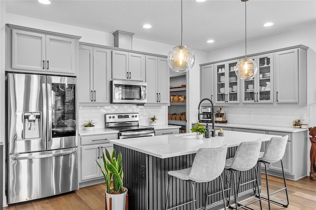 kitchen with stainless steel appliances, light wood-style flooring, and gray cabinetry