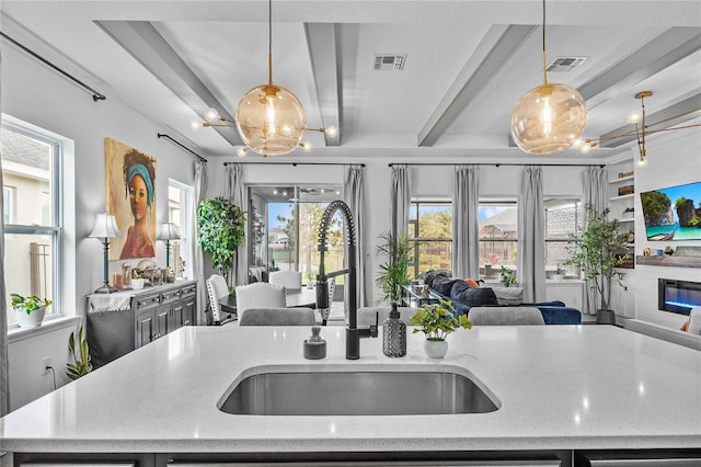 kitchen with beam ceiling, visible vents, open floor plan, and a sink