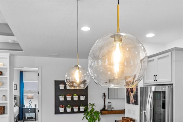 details featuring visible vents, stainless steel refrigerator with ice dispenser, decorative light fixtures, and recessed lighting