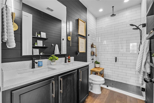 bathroom with wood finished floors, a sink, visible vents, and a shower stall