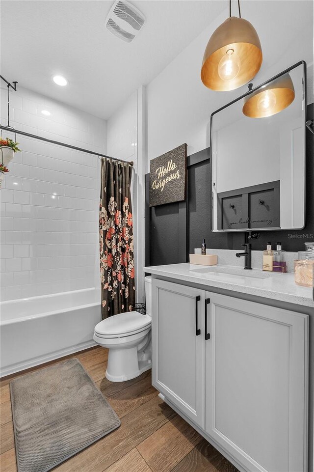 full bath featuring toilet, wood finished floors, vanity, visible vents, and shower / bath combo with shower curtain