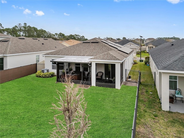 rear view of house with a lawn, a sunroom, a fenced backyard, roof with shingles, and central AC