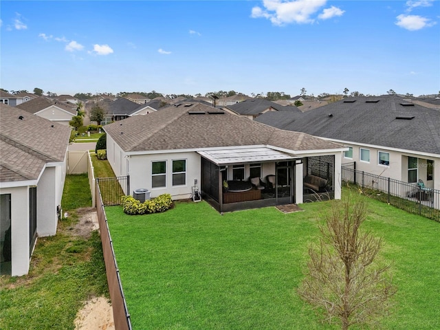 rear view of house with a shingled roof, a sunroom, a fenced backyard, and a yard