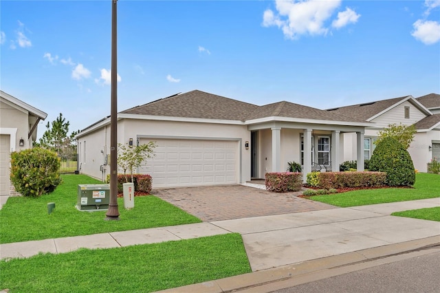 ranch-style home featuring a garage, roof with shingles, decorative driveway, stucco siding, and a front yard