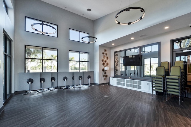 interior space featuring recessed lighting, visible vents, a towering ceiling, wood finished floors, and baseboards