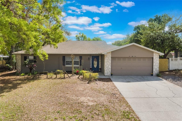 ranch-style home with a garage, fence, driveway, stone siding, and stucco siding