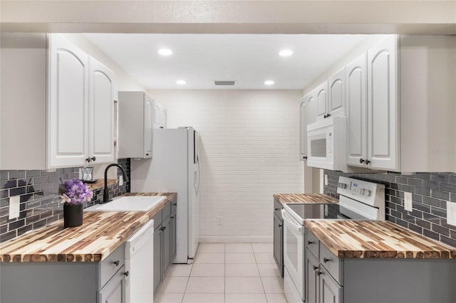 kitchen with visible vents, white appliances, wooden counters, a sink, and light tile patterned floors