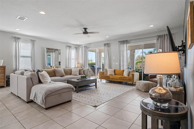 living room with a textured ceiling, light tile patterned flooring, recessed lighting, a ceiling fan, and visible vents