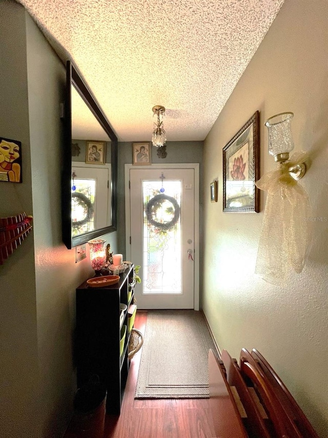 doorway to outside featuring a textured ceiling and wood finished floors