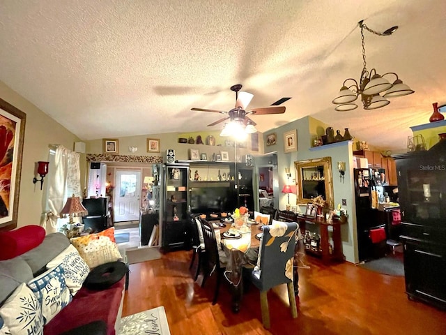 dining room featuring vaulted ceiling, a textured ceiling, ceiling fan with notable chandelier, and wood finished floors