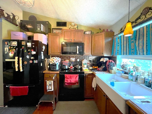 kitchen featuring black appliances, a textured ceiling, vaulted ceiling, and light countertops