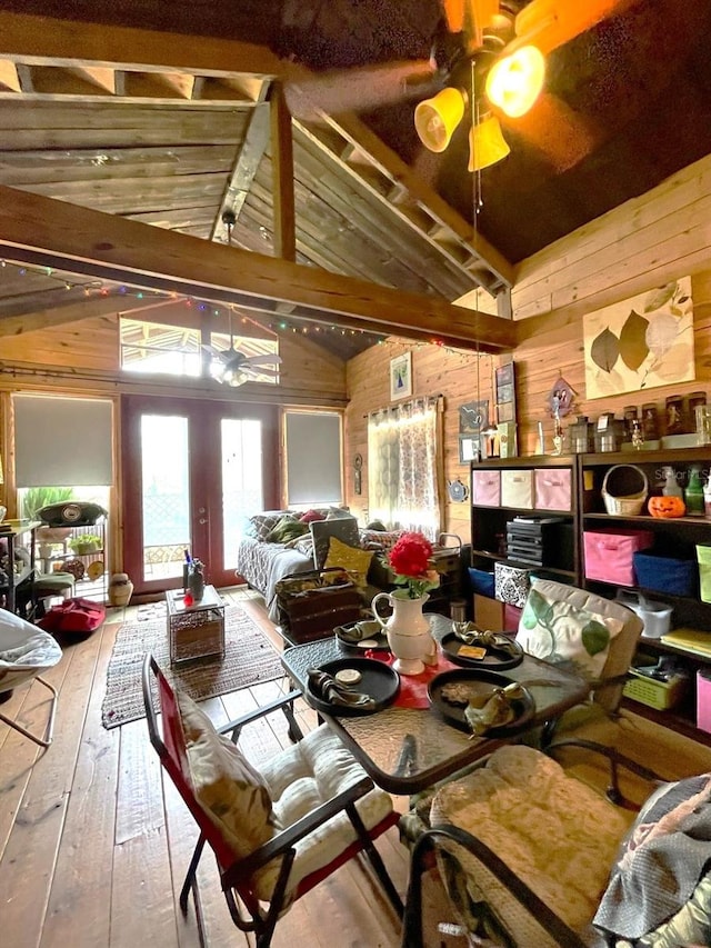 dining space featuring a ceiling fan, wood-type flooring, wooden walls, and french doors