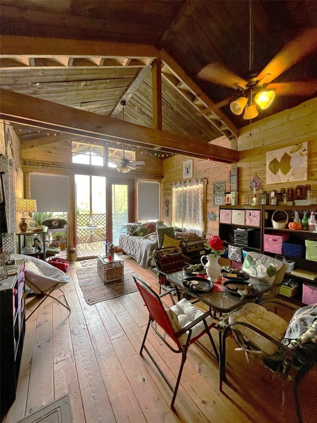 dining space with wood-type flooring, wooden walls, vaulted ceiling, and a ceiling fan
