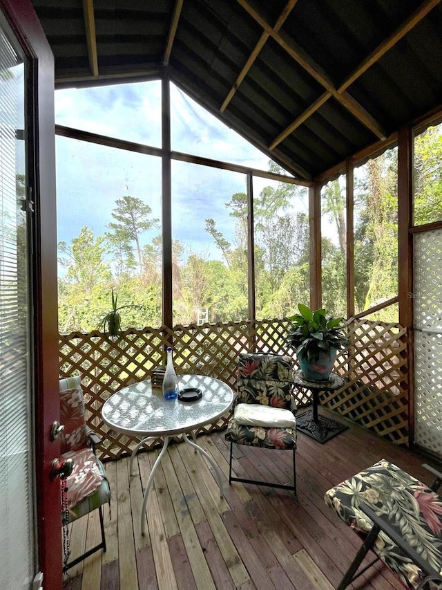 unfurnished sunroom with vaulted ceiling with beams