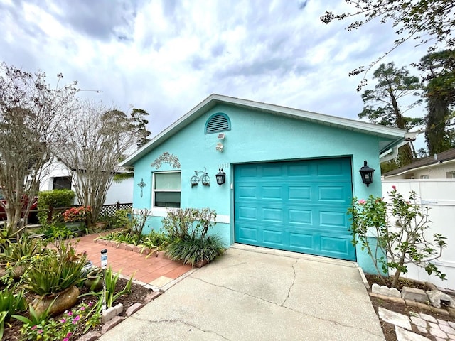 ranch-style home featuring driveway, fence, and stucco siding