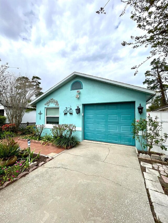 ranch-style home featuring driveway, an attached garage, and stucco siding