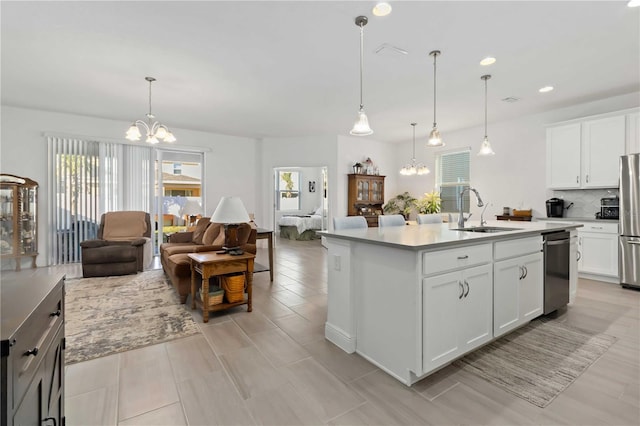 kitchen featuring appliances with stainless steel finishes, open floor plan, a sink, and a chandelier