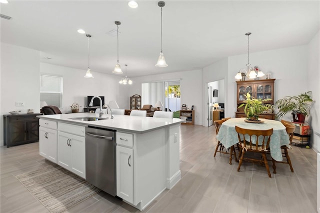 kitchen featuring pendant lighting, light countertops, stainless steel dishwasher, a kitchen island with sink, and a sink