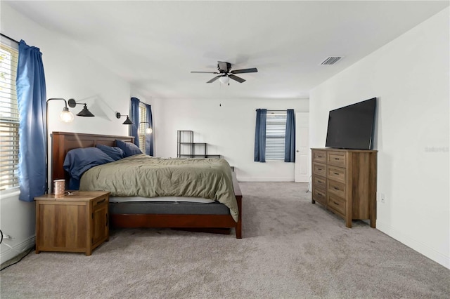 bedroom with ceiling fan, visible vents, baseboards, and light colored carpet