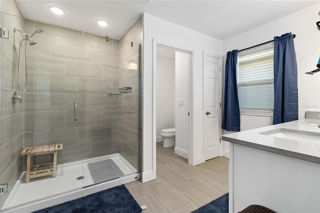 full bath with toilet, a stall shower, baseboards, and vanity