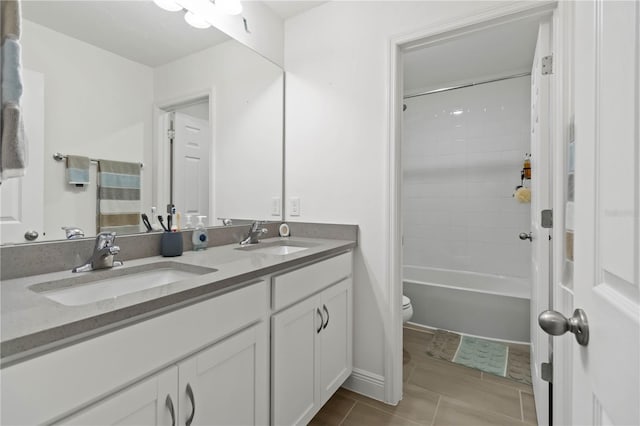 bathroom with double vanity, tile patterned flooring, a sink, and toilet