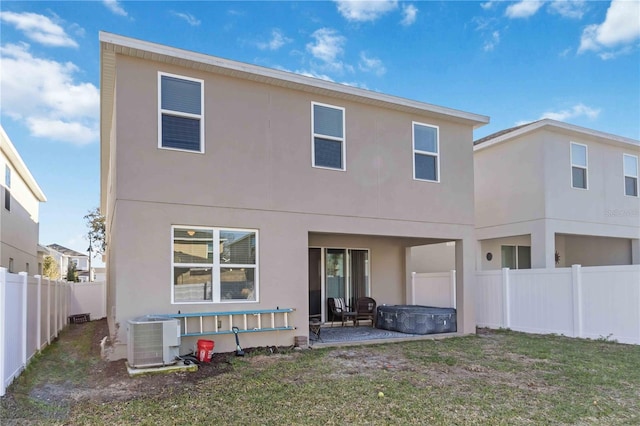 back of property featuring a fenced backyard, a lawn, central AC, and stucco siding