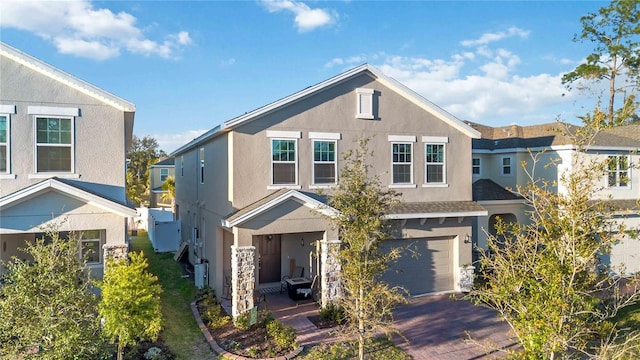 traditional home with a garage, decorative driveway, and stucco siding