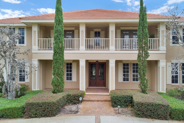 view of front of home featuring french doors, a tile roof, and stucco siding