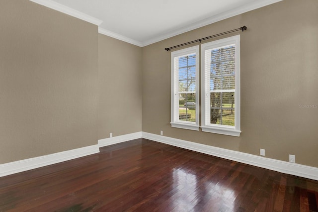 empty room featuring crown molding, hardwood / wood-style flooring, and baseboards